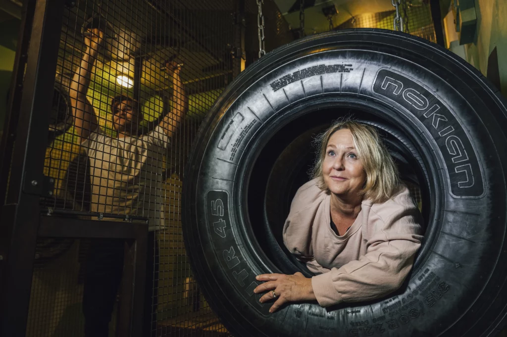 Kvinna som tar sig igenom ett traktordäck vid sidan av en yngre man som går armgång