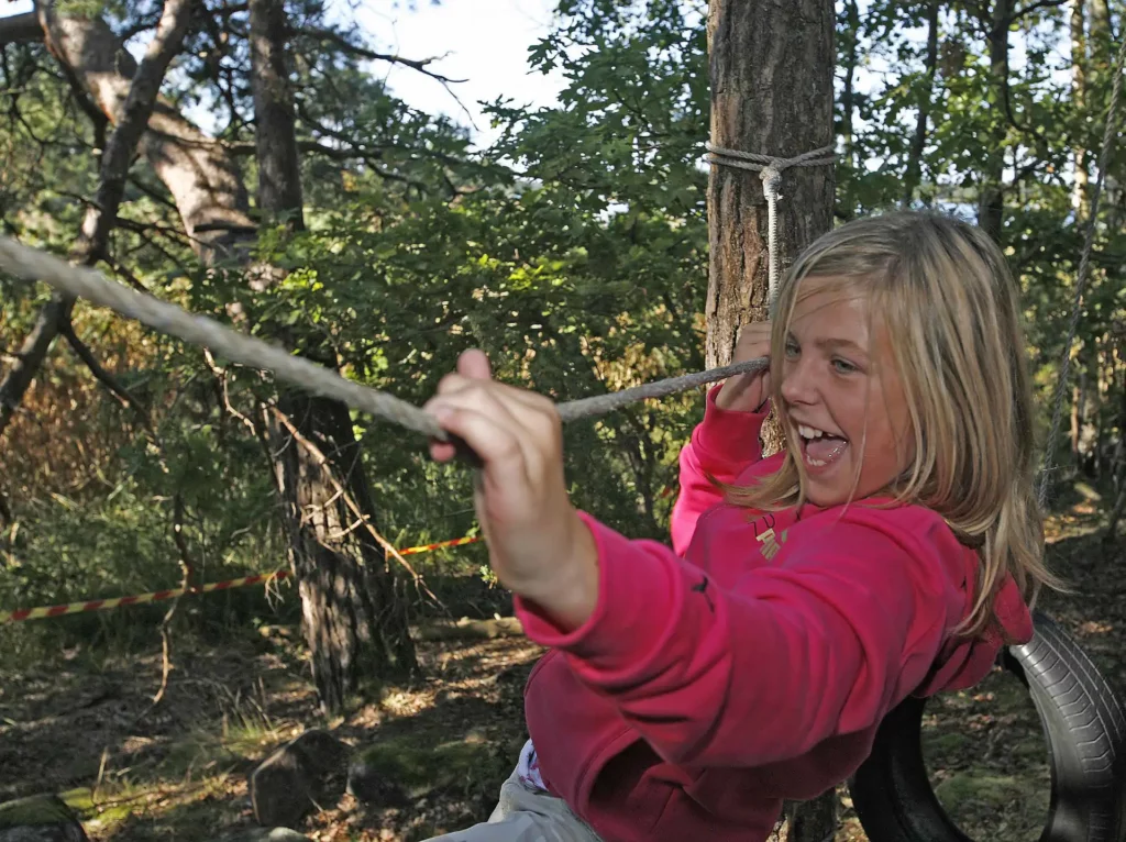 flicka klättrar i rep mellan två träd