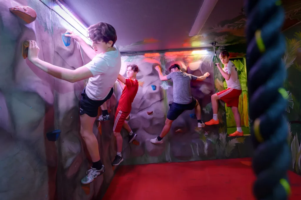 fyra killar klättrar på en klättervägg i ett rum