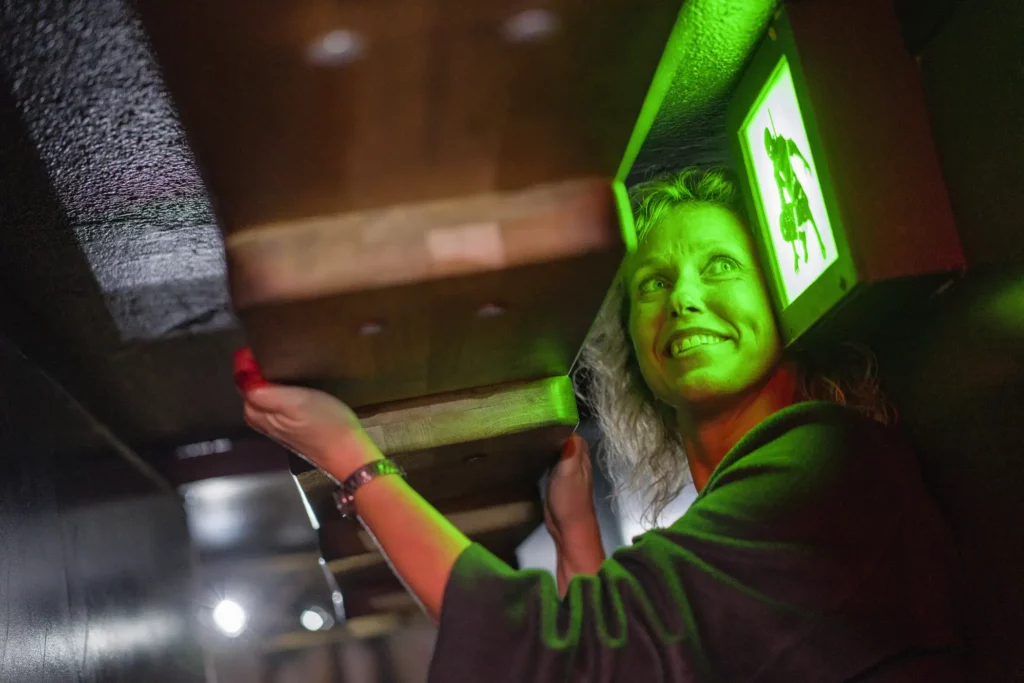 Glad kvinna klättrar och tittar på en grön upplyst bild av en ninja